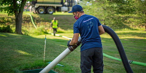 Homme avec un camion vacuum qui pompe le milieu filtrant d’une installation septique écoresponsable Ecoflo.