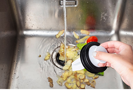 Vegetable peels and other food scraps being flushed down an Insinkerator Evolution garbage disposal system.