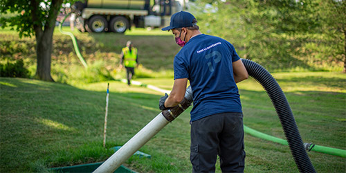 Homme avec un camion vacuum qui pompe le milieu filtrant d’une installation septique écoresponsable Ecoflo.