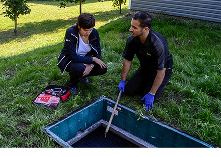 Técnico del servicio local de Premier Tech explicando el mantenimiento de una fosa séptica con biofiltro Ecoflo a un cliente.