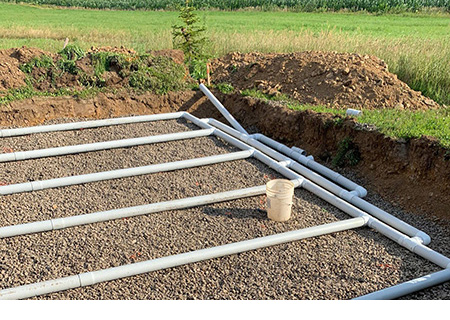 Installation d’un champ d’épuration, également connu sous le nom de champ de lixiviation, y compris des tuyaux en PVC et un lit de gravier propre.