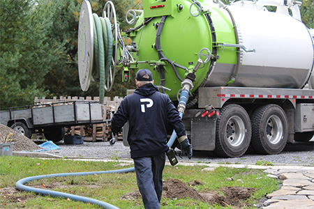 Premier Tech technician walking toward a vacuum truck that pumps sludge from septic systems. 