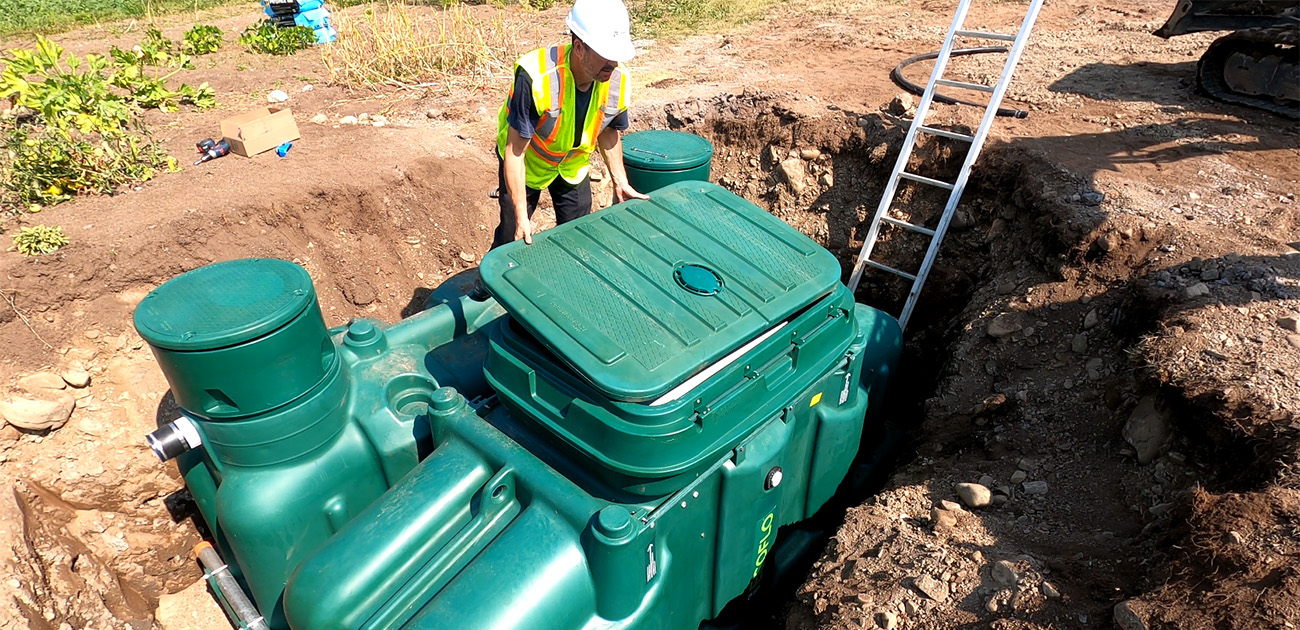 Professionnel des eaux usées installant le biofiltre Ecoflo Pack sur une propriété rurale au Québec, Canada.