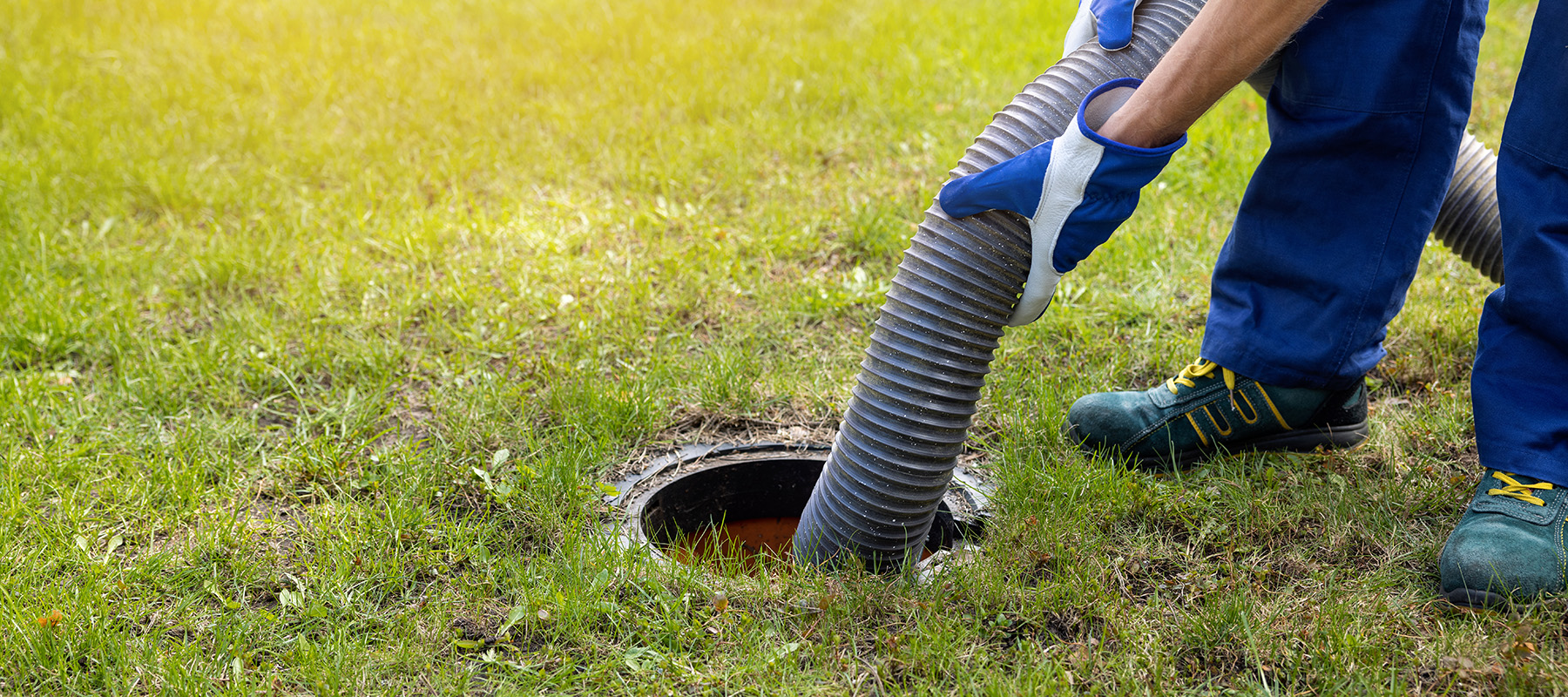 Septic pumper using a hose to empty sludge from a residential septic tank.