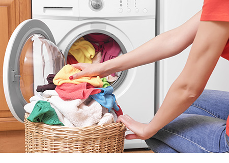 Une femme chargeant du linge dans une machine à laver reliée à une installation septique.