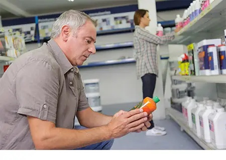 Homme qui choisit un additif pour fosse septique dans une quincaillerie.