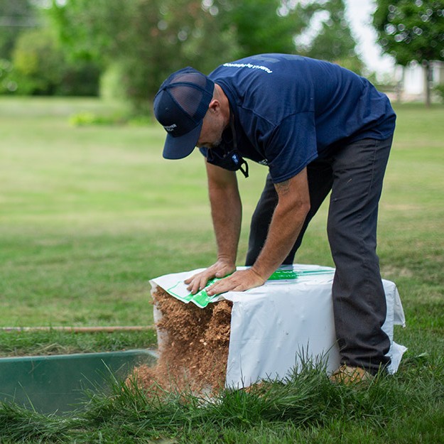 Man installing a coconut husk fragment filter in an Ecoflo biofilter septic system.