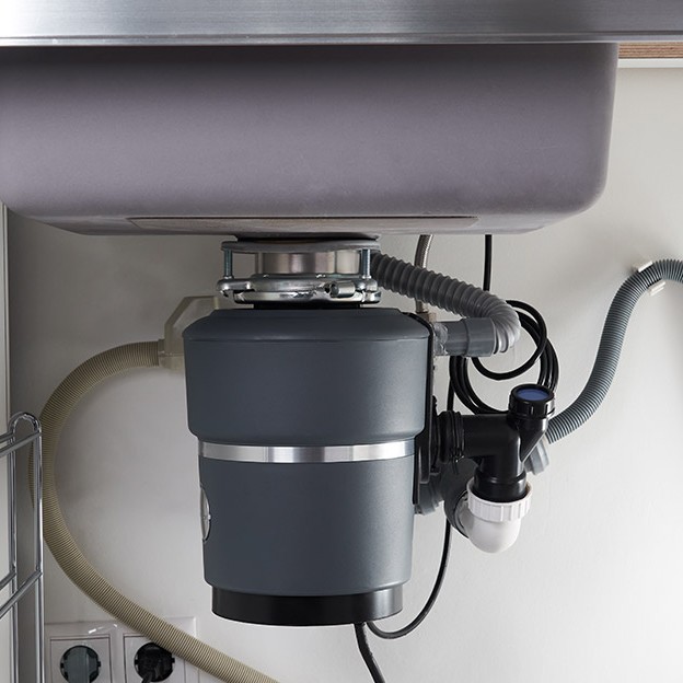 Garbage disposal system installed under a kitchen sink in a residential property.