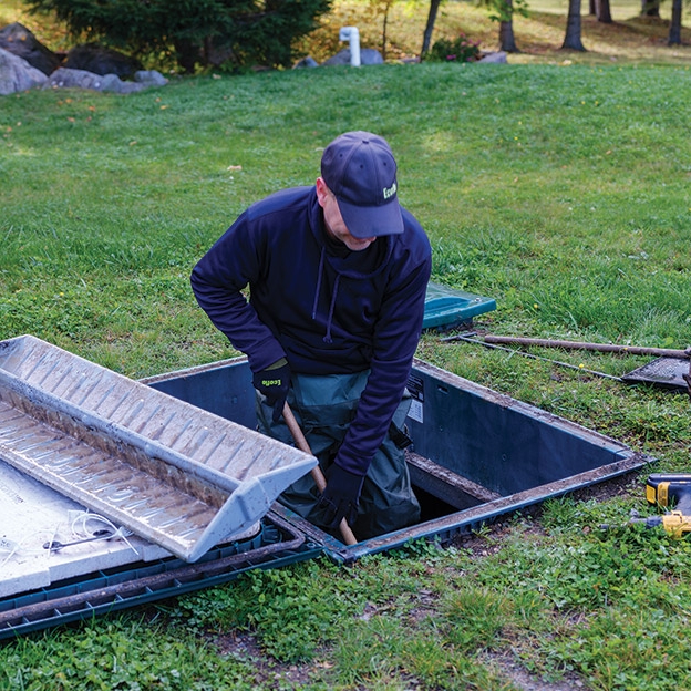 Technicien de service de Premier Tech qui entretient un système septique Ecoflo.