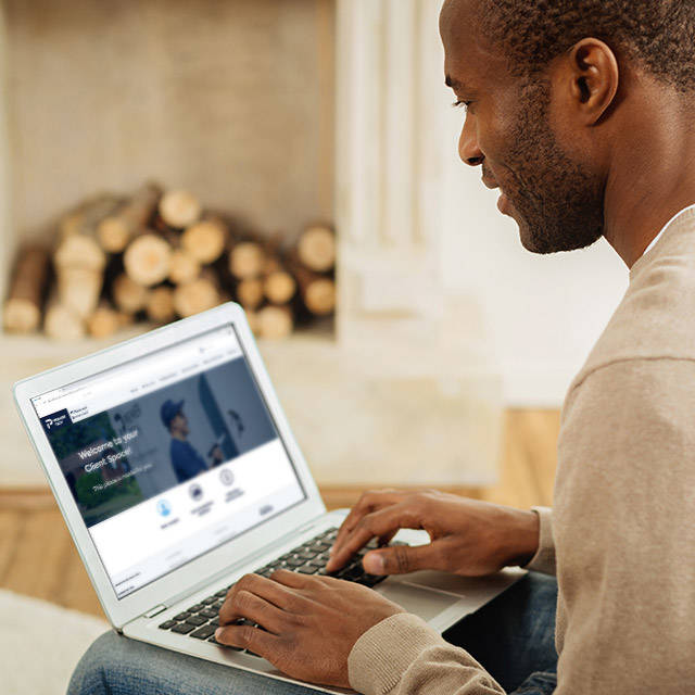 A middle-aged man using a laptop in his home to access Premier Tech Water and Environment’s Client Space.