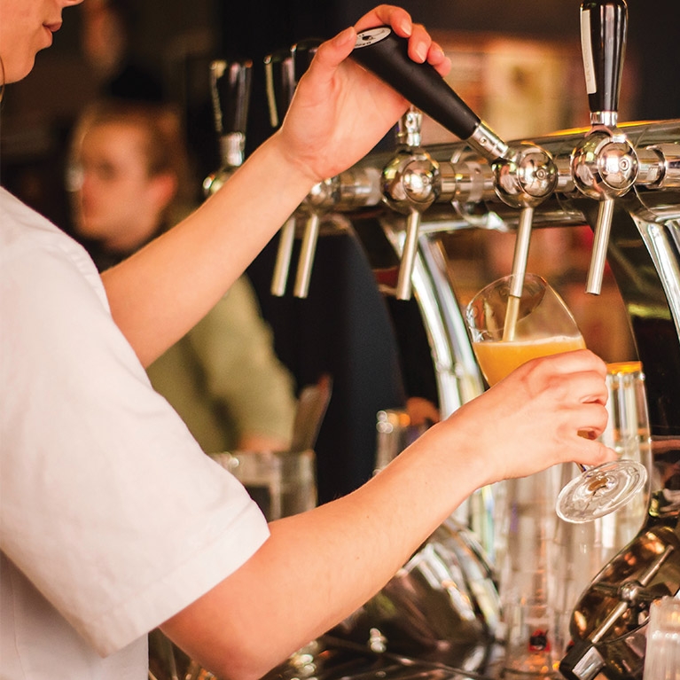 Bartender pouring craft beer from a tap at a microbrewery.