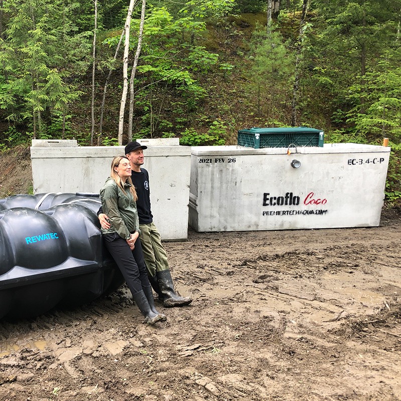 Homeowners standing beside the Rewatec rainwater harvester and the Ecoflo biofilter from Premier Tech Water and Environment.