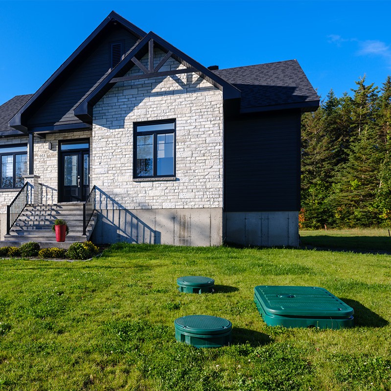 Green lids of the Ecoflo biofilter septic system installed on a rural residential property with a small lot.