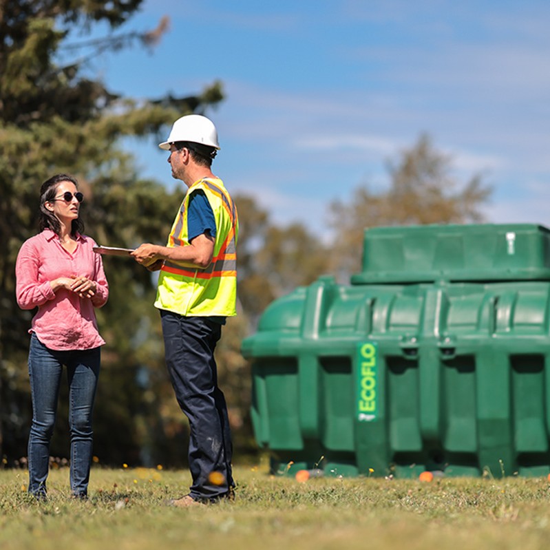 Premier Tech Water and Environment installer and customer standing in front of the polyethylene Ecoflo biofilter septic system.