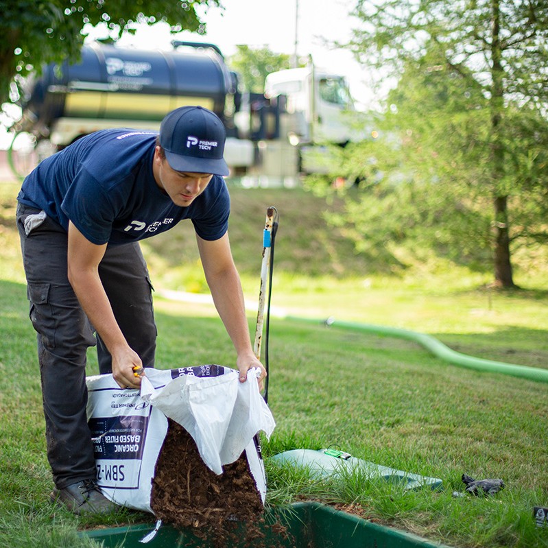 Premier Tech Water and Environment service technician installing a layer of peat moss in the Ecoflo biofilter septic system.