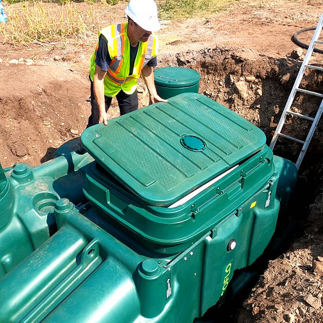 Professionnel des eaux usées installant le biofiltre Ecoflo Pack sur une propriété rurale au Québec, Canada.