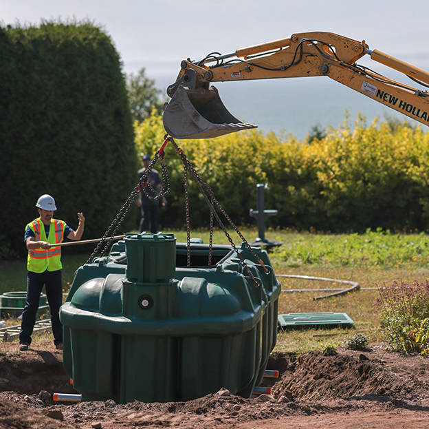 Excavator and septic installers lowering the Ecoflo biofilter septic system into a residential property.