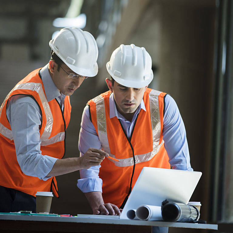 Premier Tech Water and Environment technicians in orange vests looking at design plans for a wastewater treatment plant in India.