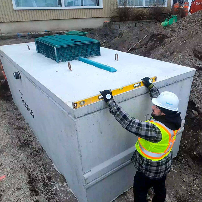 Septic system installer levelling the concrete Ecoflo compact biofilter on a residential property in Pennsylvania.