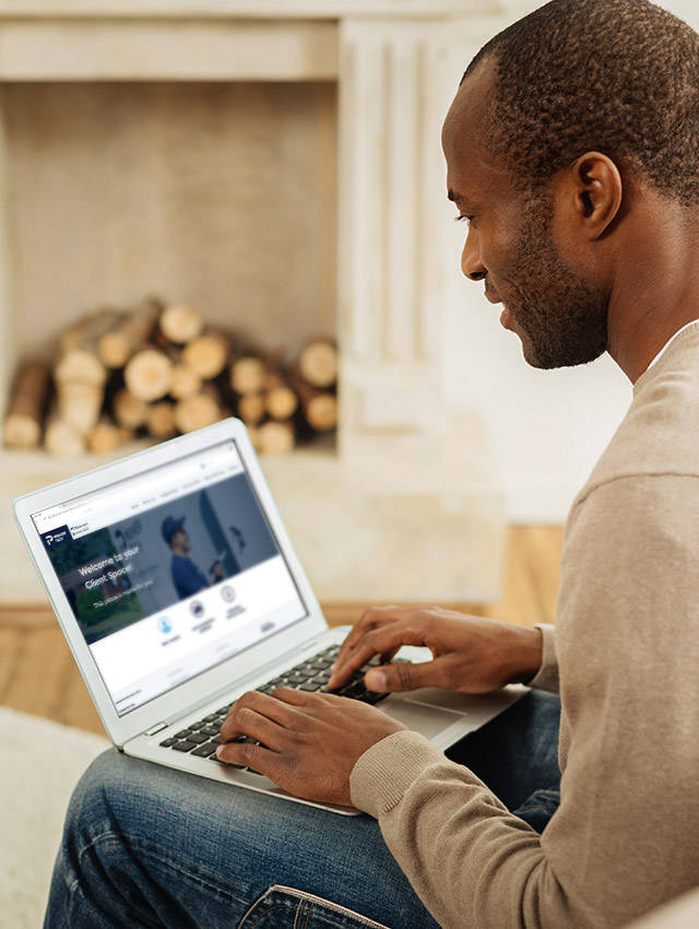 A middle-aged man using a laptop in his home to access Premier Tech Water and Environment’s Client Space.