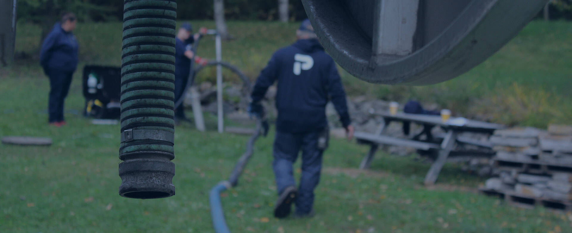 Vacuum truck hose in front of Premier Tech technicians performing a sludge removal.