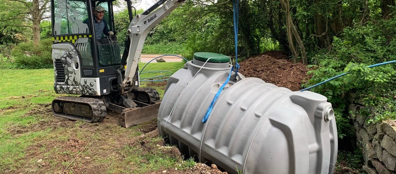 Crane lifting a septic tank into position during installation