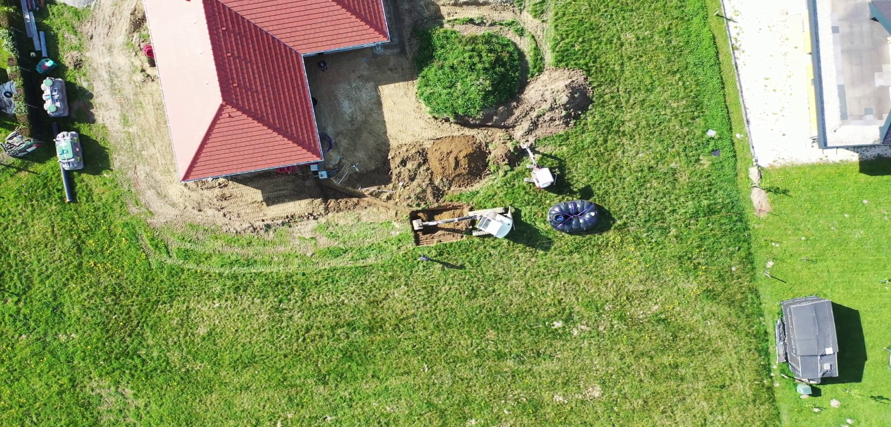 Prise de vue aérienne d'une maison avec un récupérateur d'eau de pluie Rewatec sur la pelouse