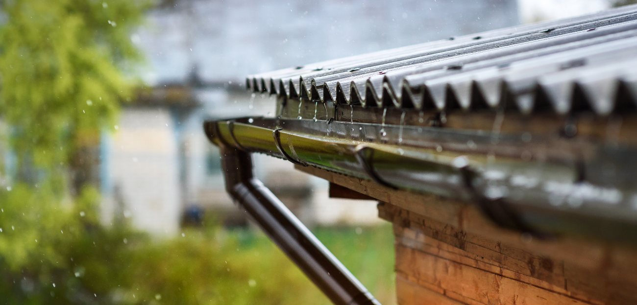 Pluie qui tombe dans une goutière sur un toit en tôle