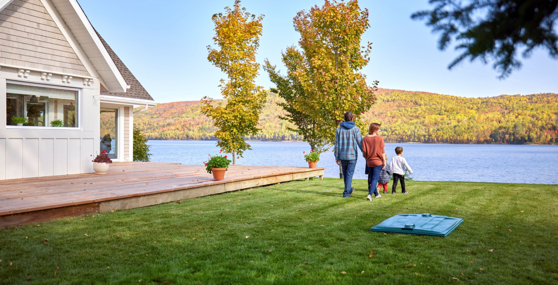 Famille se promenant sur le bord du lac Pohénégamook devant le couvert d'un biofiltre Ecoflo.