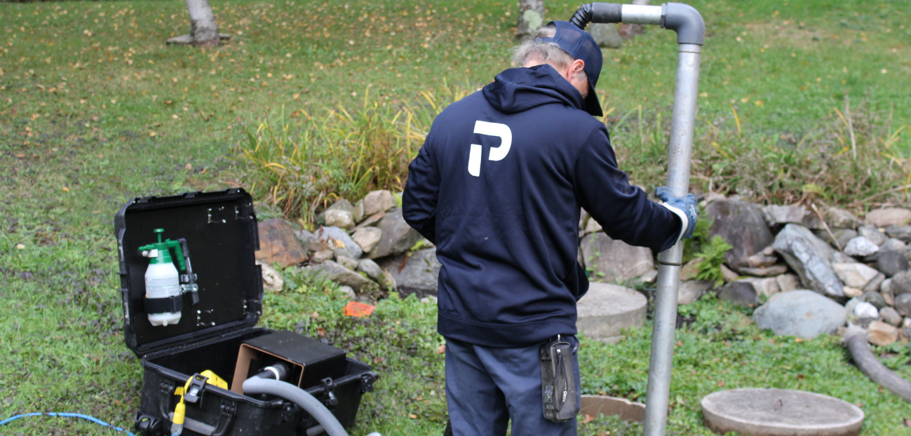 Technicien Premier Tech effectuant le soutirage de boues dans une installation septique Bionest défaillante.