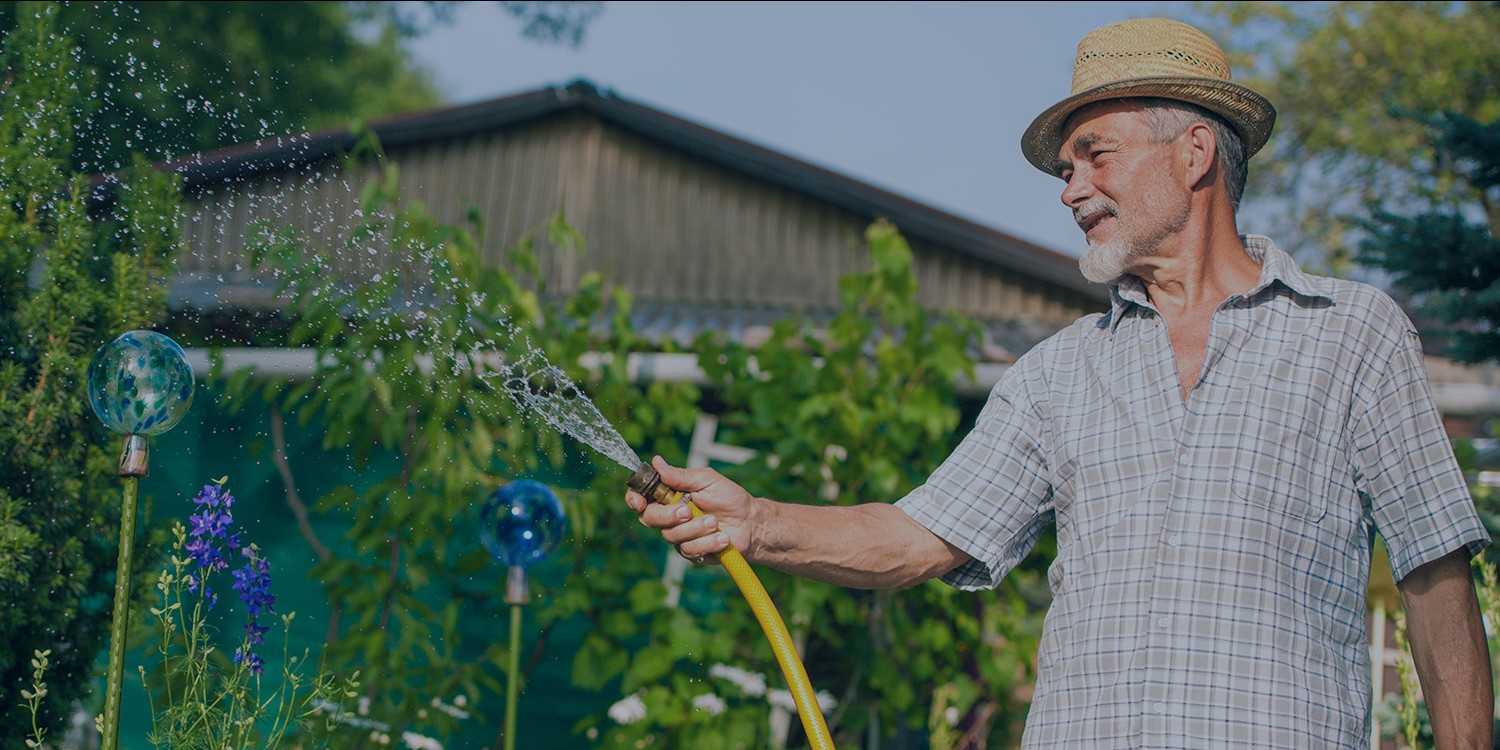 Man watering his garden with water collected from the Rewatec rainwater harvesting system.