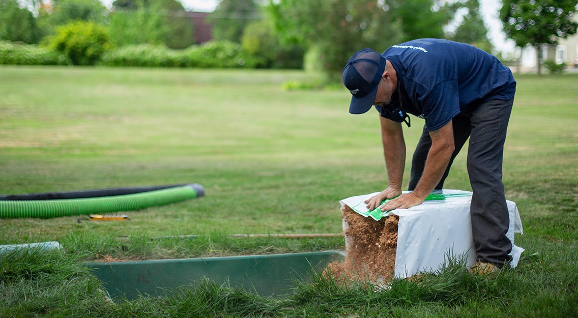 Man installing a coconut husk fragment filter in an Ecoflo biofilter septic system.