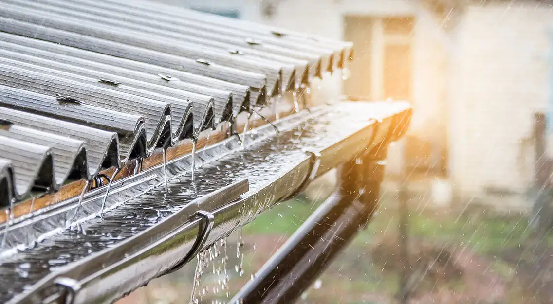 Regen wird beim Abfluss von der Dachfläche in Regenrinnen aufgefangen   Warum Sie Regenwasser sammeln sollten