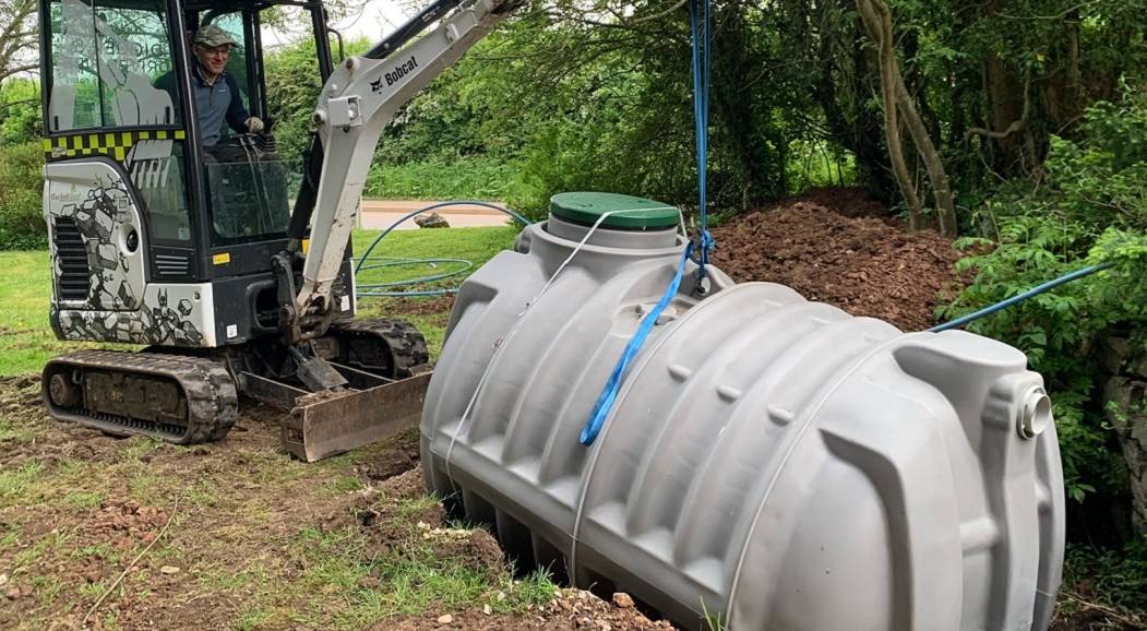 Crane lifting a septic tank into position during installation