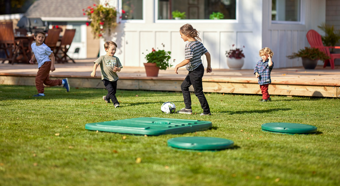 Enfants qui jouent dans la cour proche de couvercles du biofiltre Ecoflo