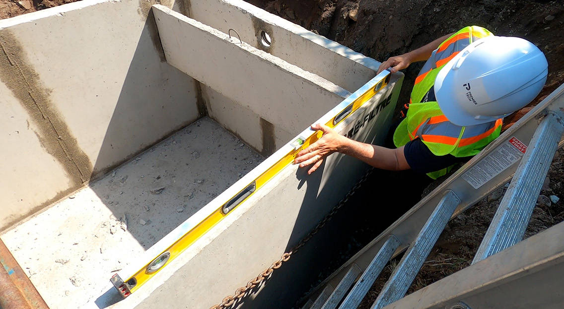 Premier Tech Water and Environment installer making sure that a septic tank is level before backfilling.