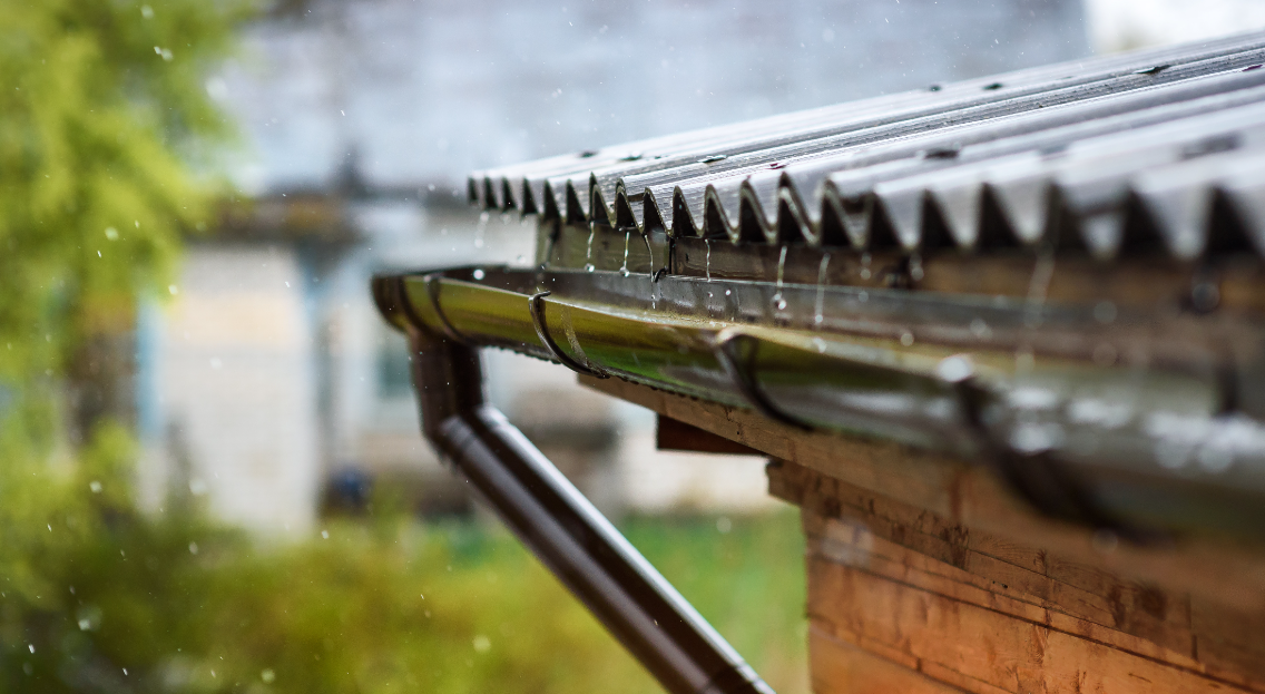 Pluie qui tombe dans une goutière sur un toit en tôle