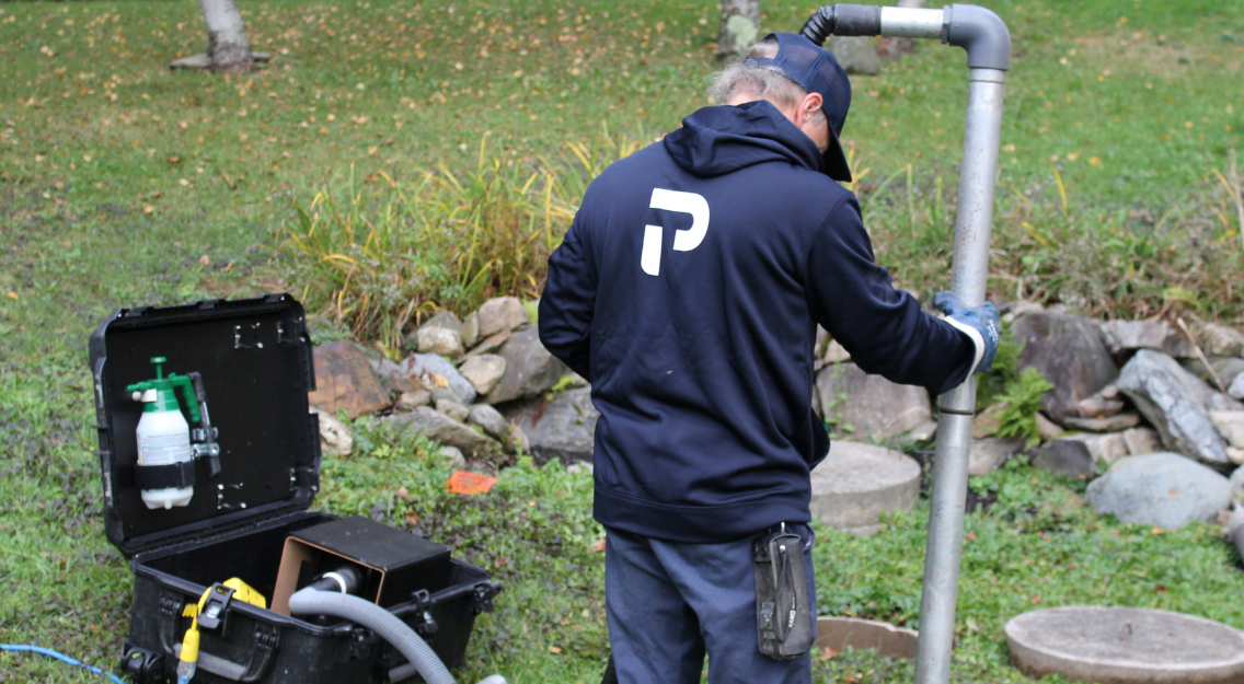 Technicien Premier Tech effectuant le soutirage de boues dans une installation septique Bionest défaillante.