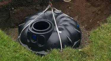 Excavator lowering Premier Tech Water and Environment's 3,000 L underground rainwater harvesting tank into a residential yard.