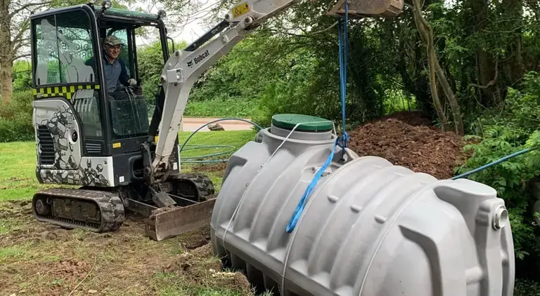 Crane lifting a septic tank into position during installation