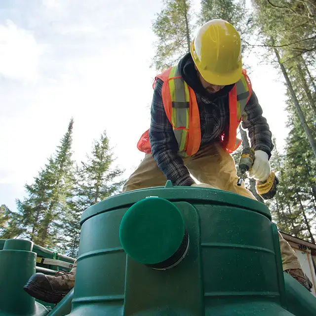 Professionnel du traitement des eaux usées installant le modèle Pack en polyéthylène de l'installation septique Ecoflo.