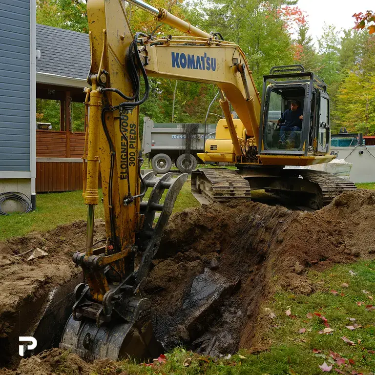 Excavateur creusant dans la terre pour retirer un système septique.