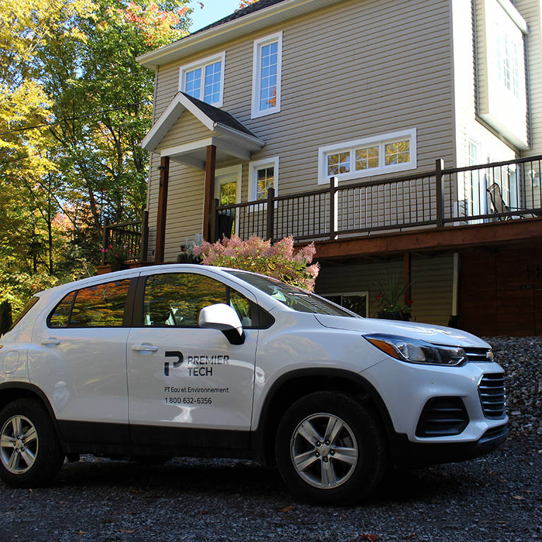 Voiture Premier Tech devant une maison pour l'entretien d'installation septique.