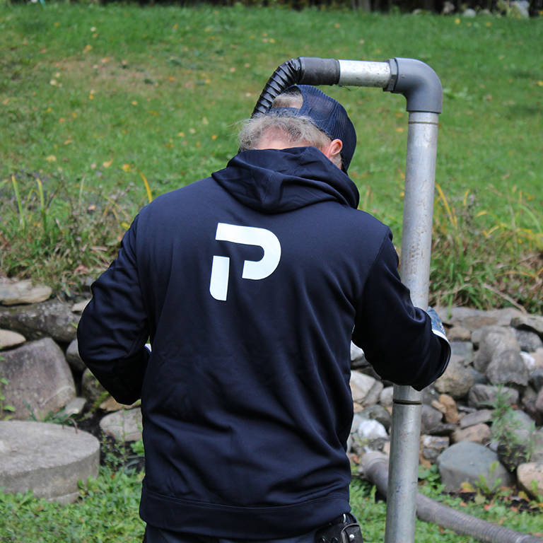 Technician racking sludge from a Bionest septic system
