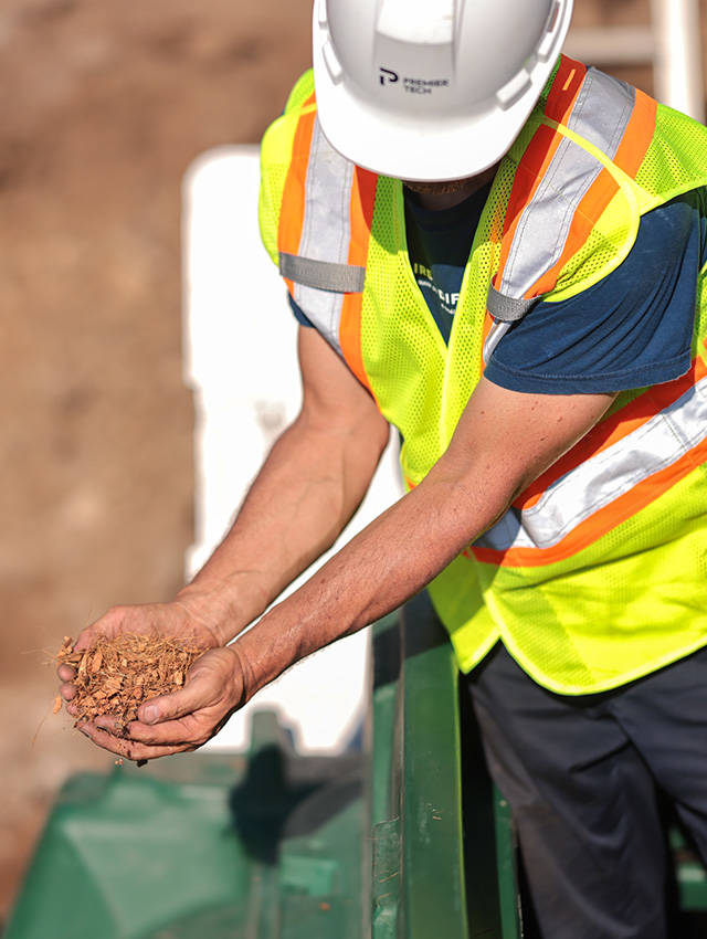 Ecoflo compact biofilter installer holding the coconut husk fragments used to remove pollutants from domestic wastewater.